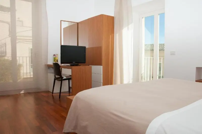 Une chambre lumineuse avec un lit et un bureau près d'une fenêtre.
