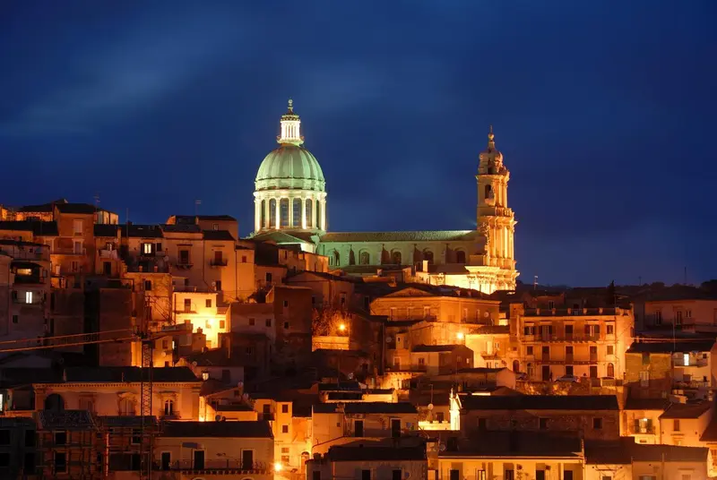 Vue nocturne d'une ville historique avec une cathédrale illuminée.