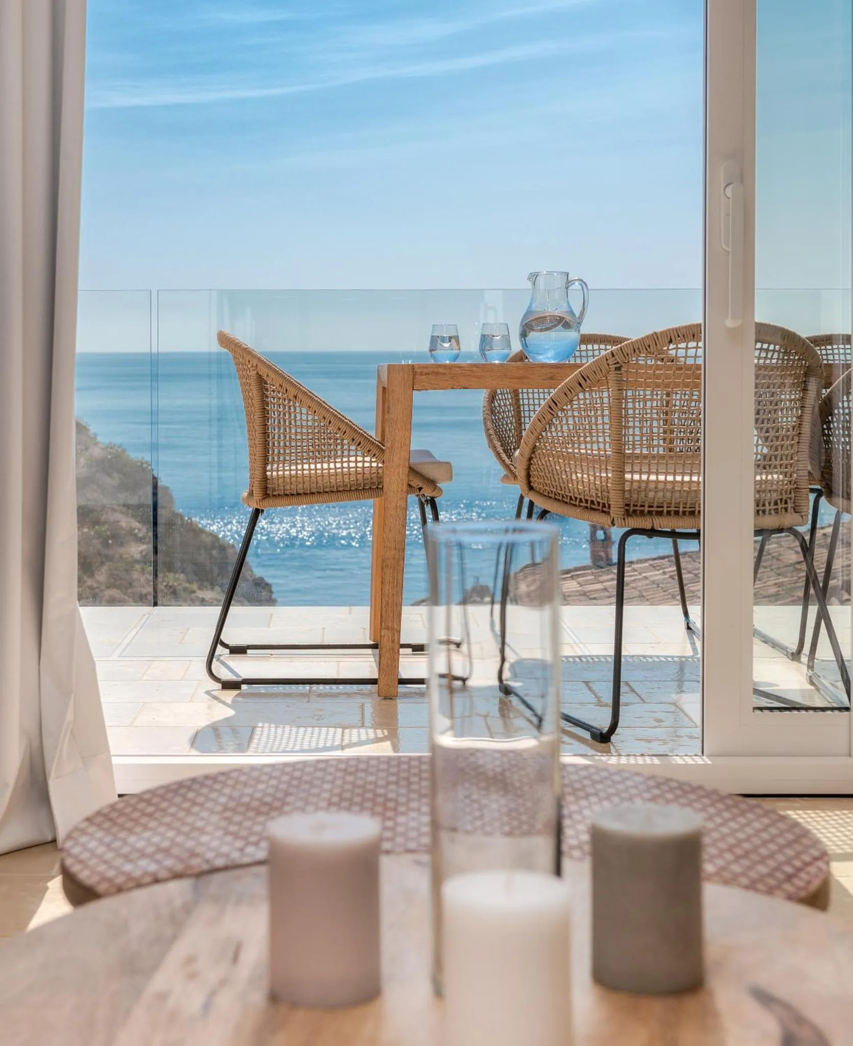 Table et chaises en rotin sur une terrasse avec vue sur la mer.