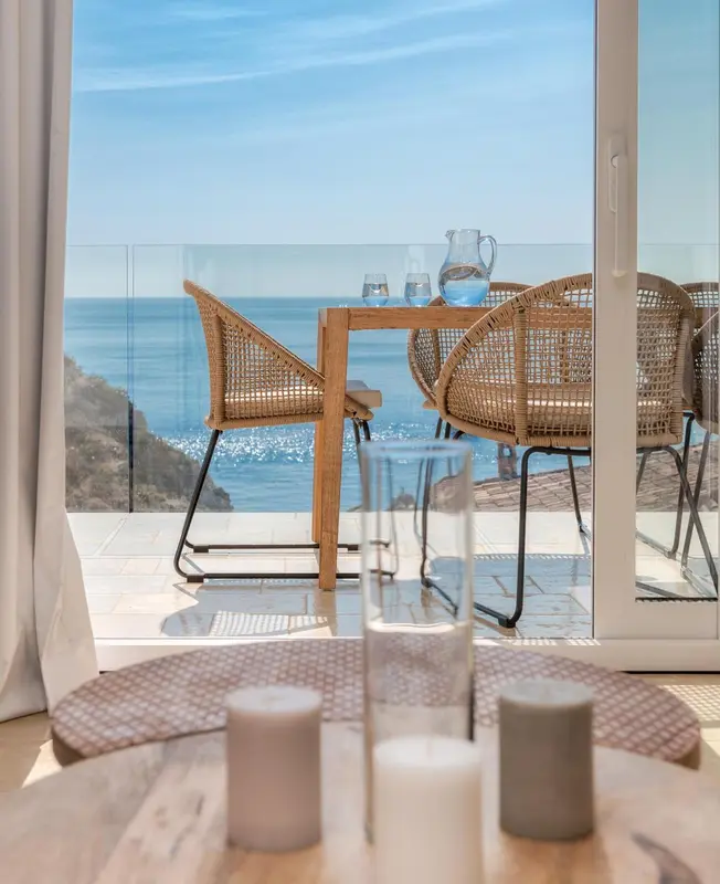 Table et chaises en rotin sur une terrasse avec vue sur la mer.