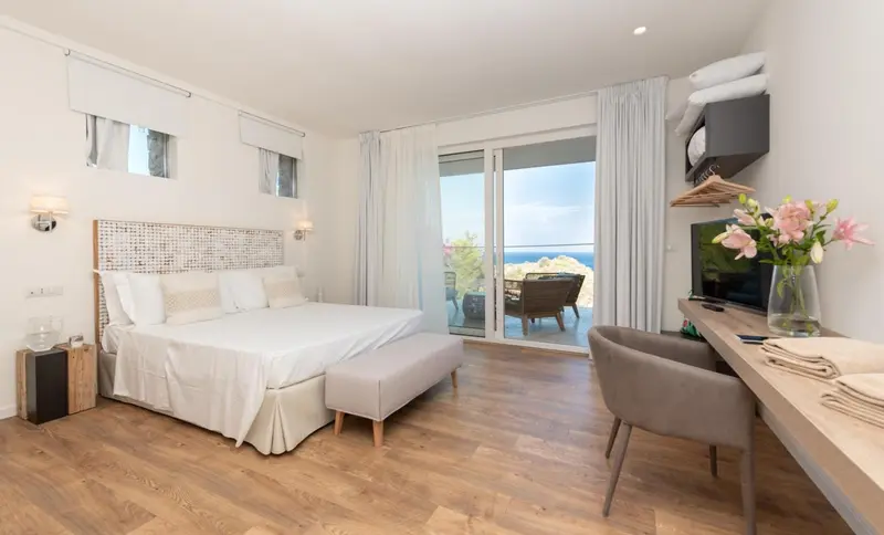 Chambre lumineuse avec un grand lit et un accès à une terrasse.