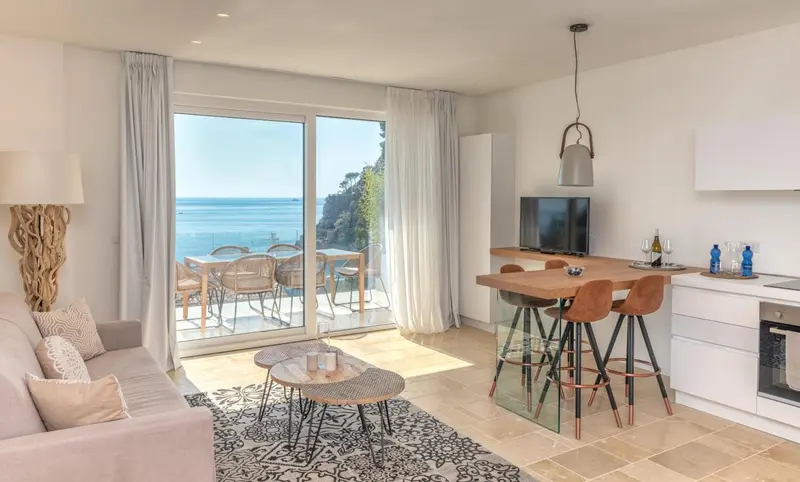 Espace de vie lumineux avec coin repas et vue sur la mer.