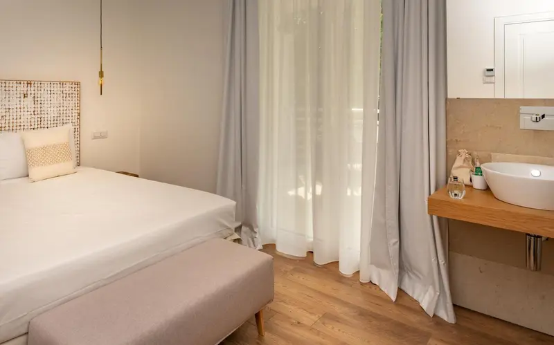 Une chambre lumineuse avec un lit et un lavabo.