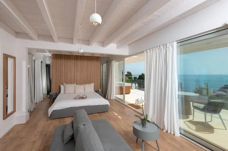 Une chambre lumineuse avec un grand lit et un accès à une terrasse vue sur mer.