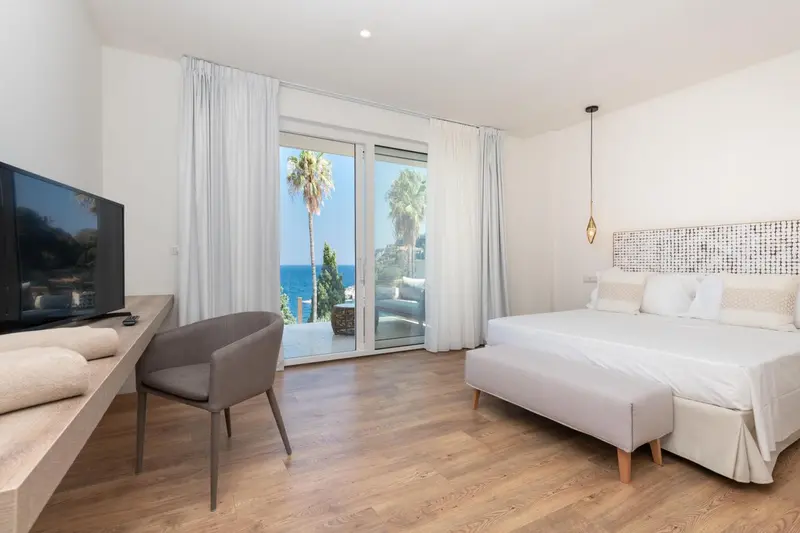Une chambre lumineuse avec un grand lit et un accès à une terrasse.