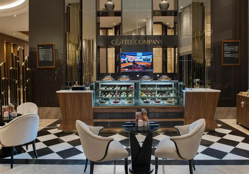 Un comptoir de pâtisseries et de boissons propose des gourmandises dans un espace lounge élégant.