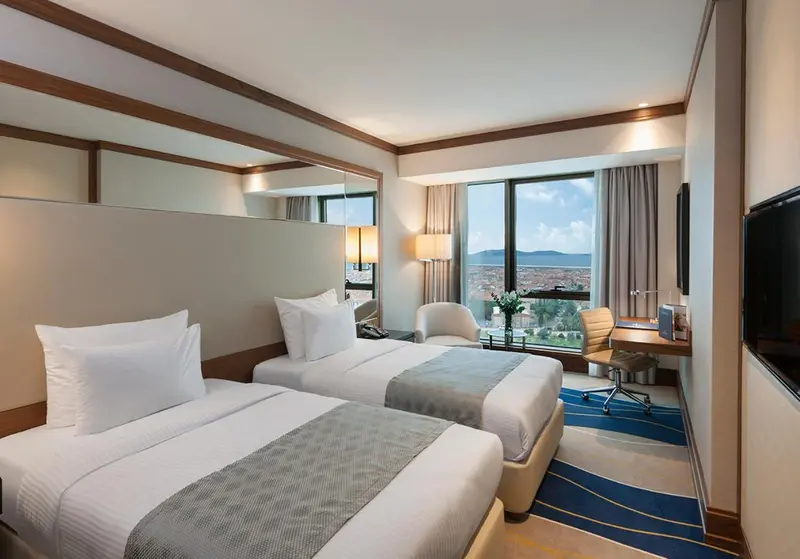Chambre d'hôtel avec deux lits simples et vue sur la ville.