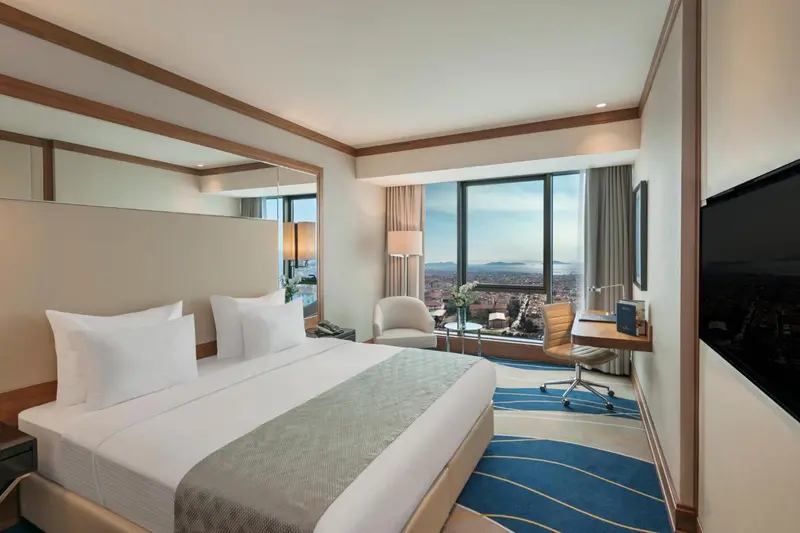 Chambre d'hôtel moderne avec un grand lit et une vue sur la ville.
