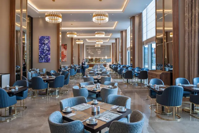 Une grande salle lumineuse est aménagée avec des tables et des chaises pour les repas.