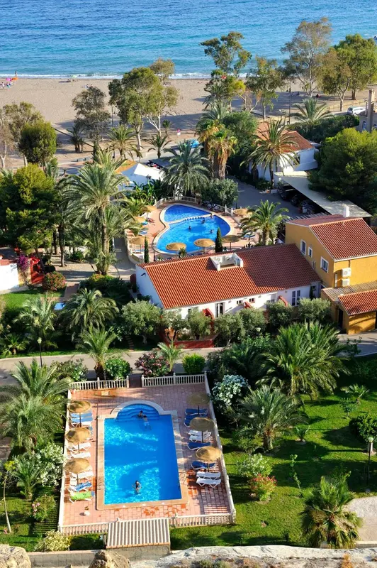 Vue aérienne d'un complexe hôtelier avec piscine et végétation luxuriante.