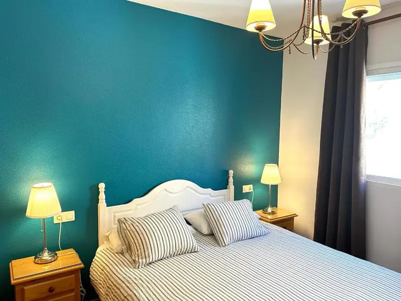 Une chambre lumineuse avec un lit double et des tables de chevet.