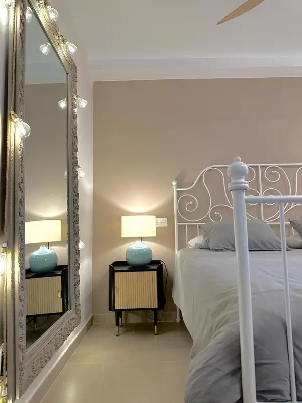 Une chambre à coucher lumineuse avec un grand miroir et un lit à baldaquin.