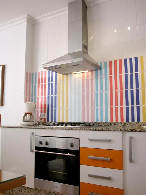 Une cuisine moderne avec des appareils en acier inoxydable et une crédence colorée.