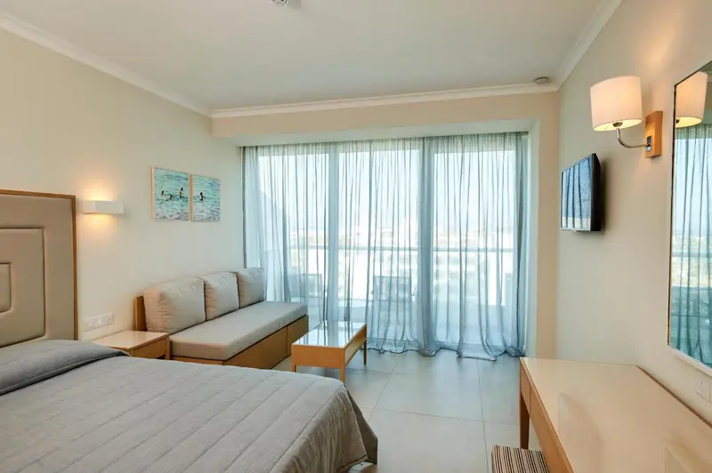 Une chambre lumineuse avec un canapé et une vue sur la mer à travers de larges fenêtres.