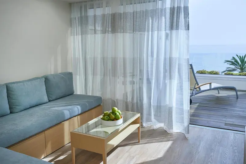 Un canapé bleu turquoise et une table basse avec des fruits sont disposés dans un espace lumineux.