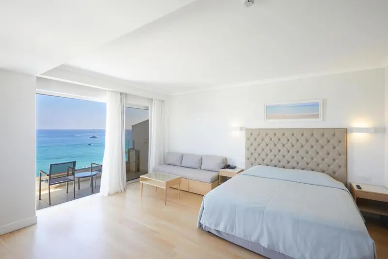 Une chambre lumineuse avec un canapé et un lit donnant sur une vue mer.