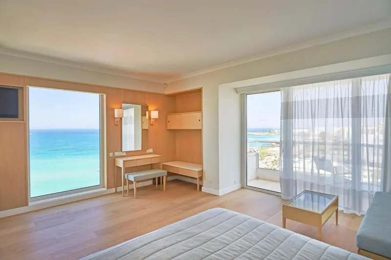 Une chambre lumineuse avec vue sur la mer et un balcon.
