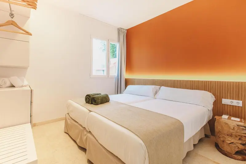 Une chambre lumineuse avec un grand lit et un mur orange.