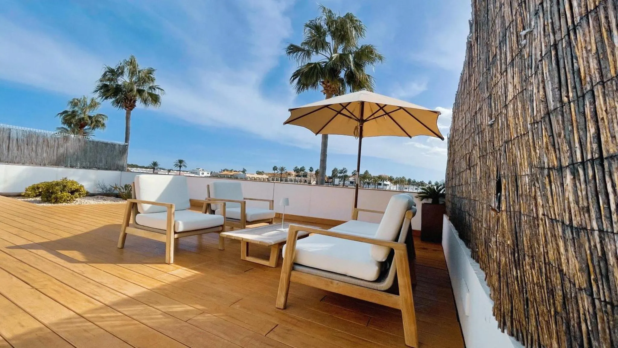 Terrasse aménagée avec mobilier de détente et parasol face à la mer.
