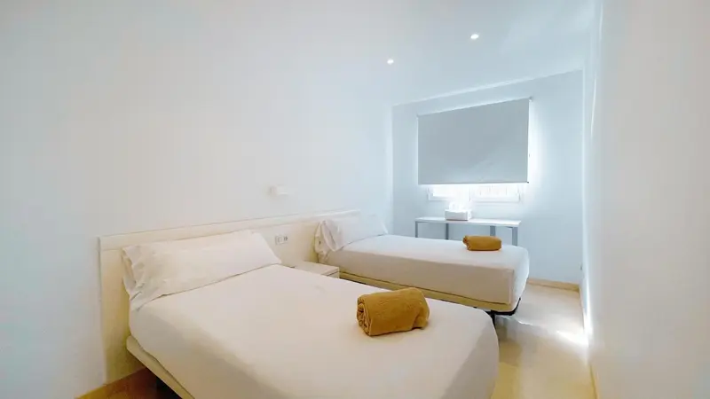 Une chambre lumineuse avec deux lits simples et une fenêtre.