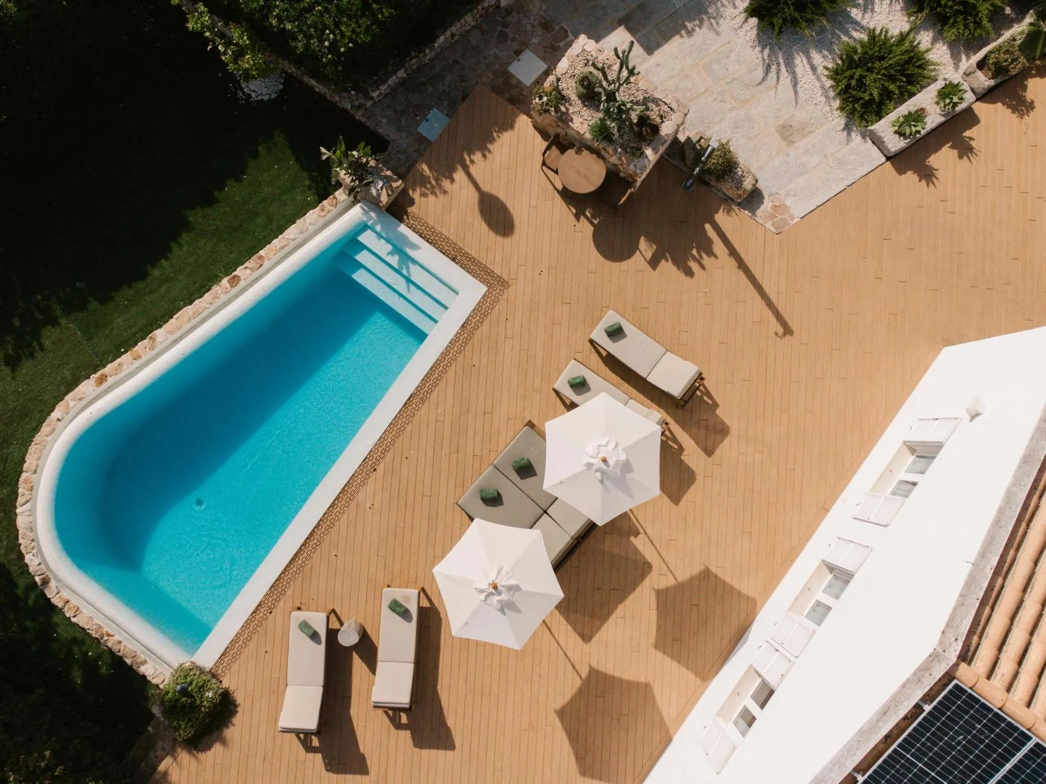Terrasse en bois avec transats et parasols autour d'une piscine rectangulaire.