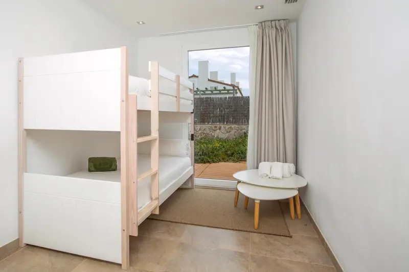 Une chambre avec un lit superposé et une vue sur un espace extérieur.