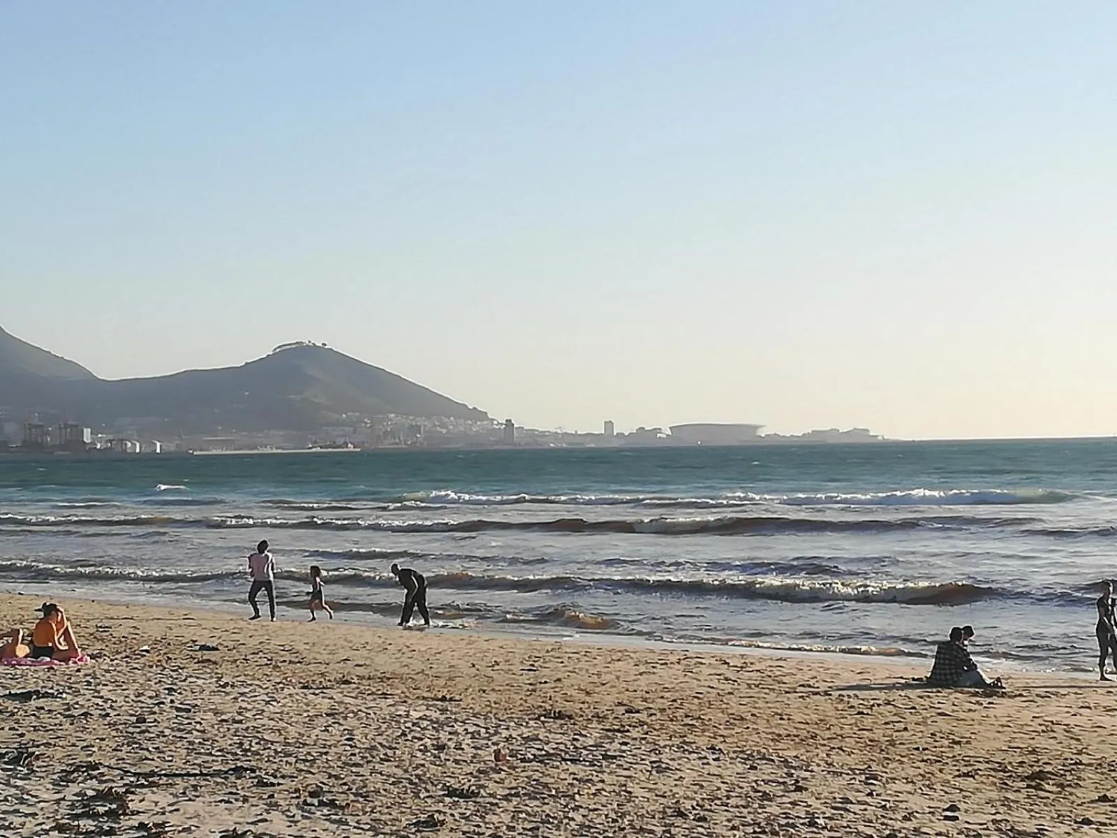 Une plage ensoleillée avec des personnes se promenant le long du rivage.