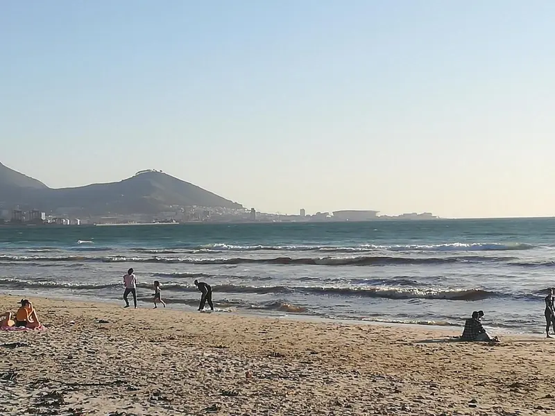 Une plage ensoleillée avec des personnes se promenant le long du rivage.