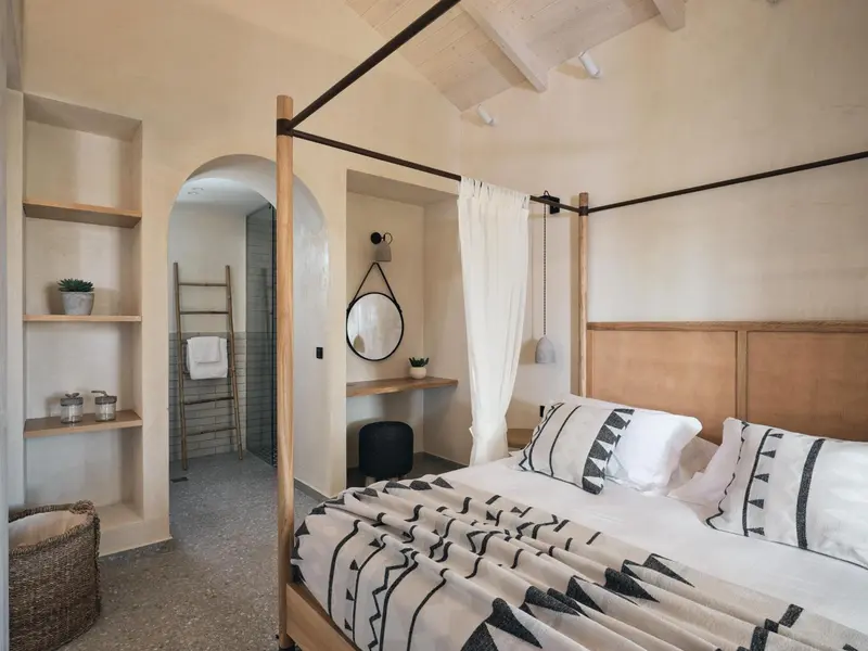 Une chambre lumineuse avec un grand lit et un espace douche ouvert.