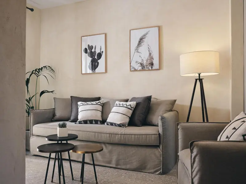 Un canapé confortable avec des coussins est éclairé par une lampe sur pied.