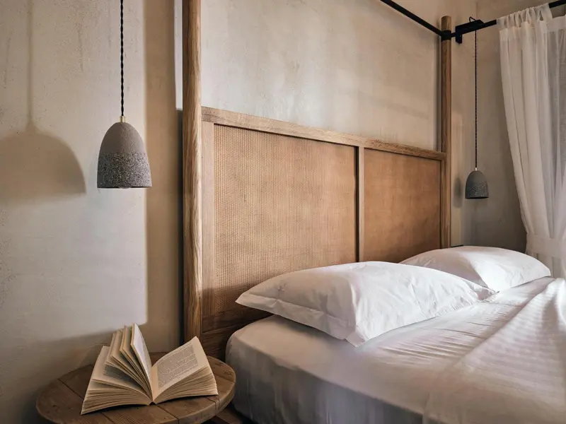 Un lit avec des oreillers blancs et une table de chevet en bois.