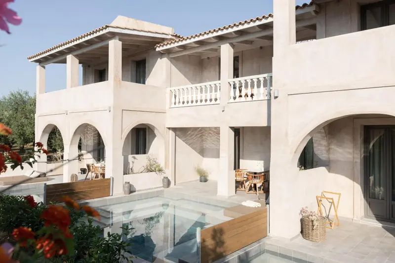 Façade d'un bâtiment blanc à deux étages avec des balcons et une petite piscine.