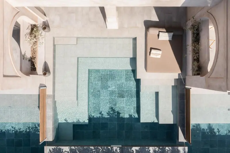 Vue aérienne d'une piscine rectangulaire entourée d'une terrasse en béton.