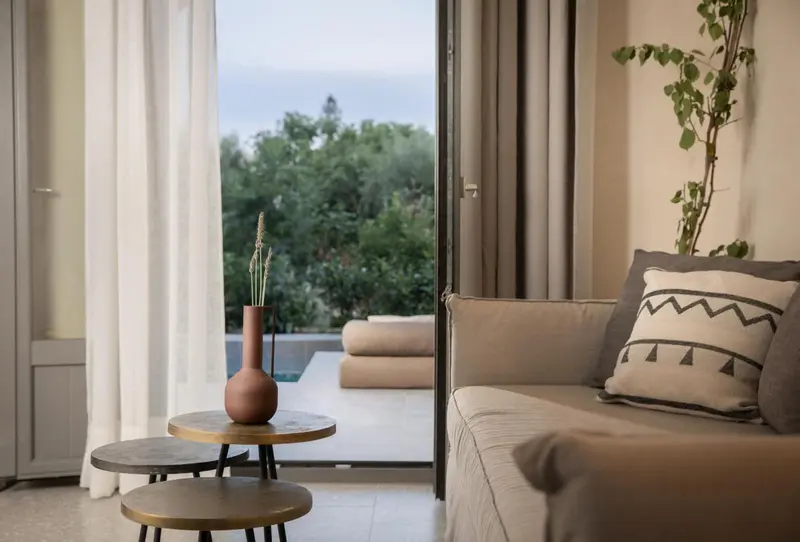 Un salon lumineux s'ouvre sur une terrasse avec vue sur la végétation.