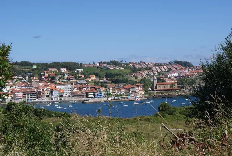 Vue d'un village côtier avec des bâtiments aux toits rouges et un port de plaisance.
