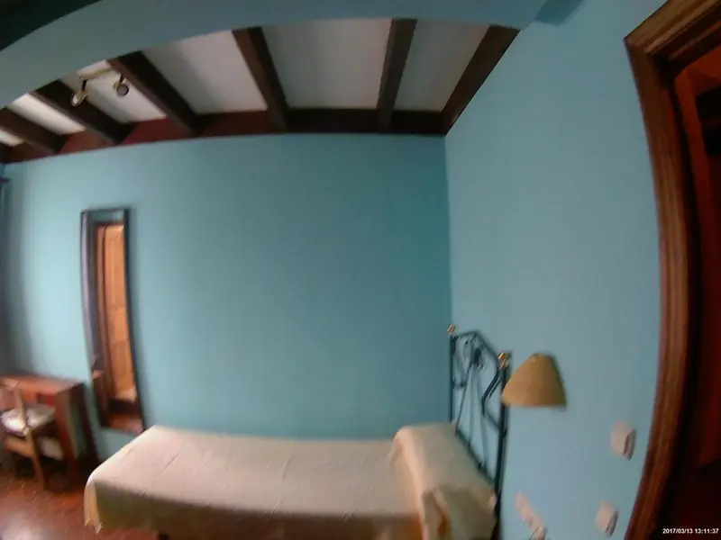 Une chambre lumineuse aux murs bleus et au plafond en bois.