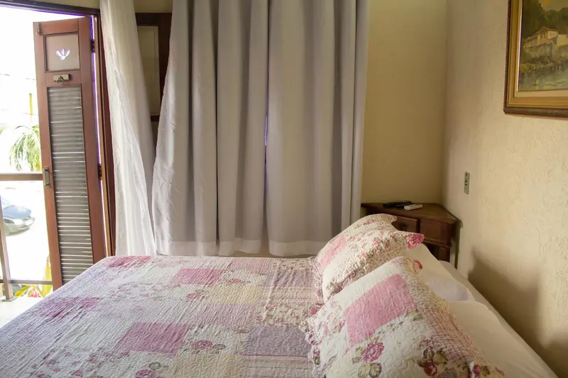 Une chambre lumineuse avec un lit recouvert d'une courtepointe florale et une porte-fenêtre.
