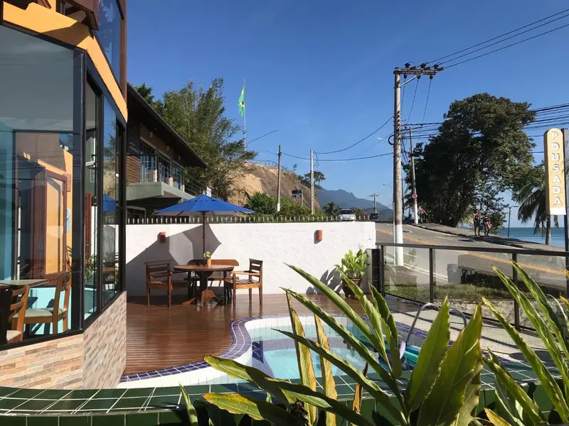 Terrasse avec tables et chaises près d'une piscine et d'une façade d'établissement.