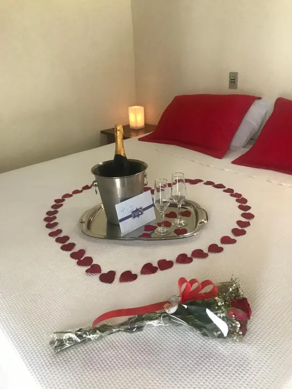 Un lit recouvert de pétales de roses avec une bouteille de champagne et des verres.