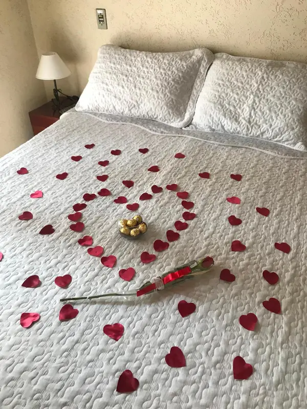 Un lit double est décoré de pétales de roses et de chocolats.