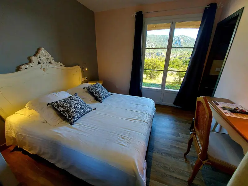 Une chambre lumineuse avec un grand lit et une vue sur un paysage montagneux.