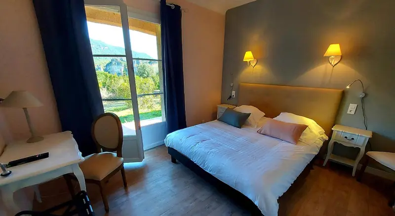 Une chambre lumineuse avec un lit double et une vue sur un paysage verdoyant.