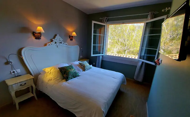Une chambre lumineuse avec un grand lit et des appliques murales.