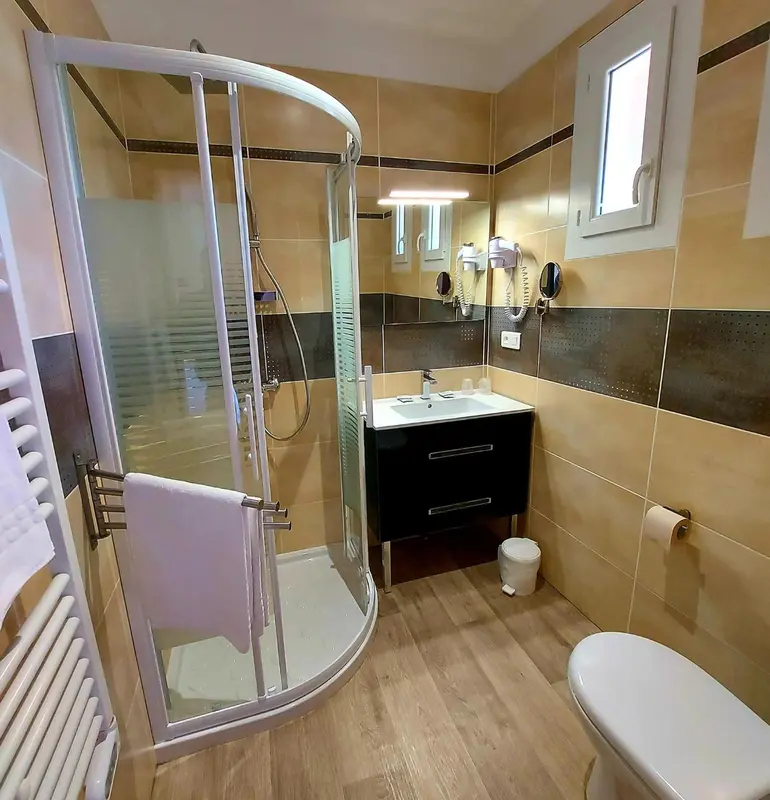 Une salle de bain moderne avec douche vitrée et carrelage beige.