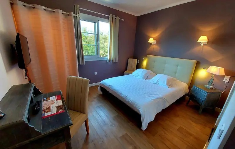 Une chambre lumineuse avec un lit double et un bureau.