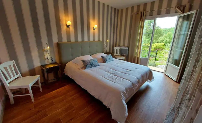 Une chambre lumineuse avec un lit double et un accès à une terrasse.