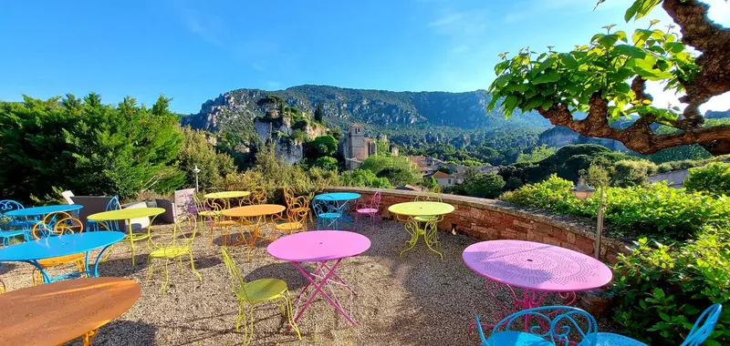 Terrasse colorée avec tables et chaises donnant sur un paysage montagneux.