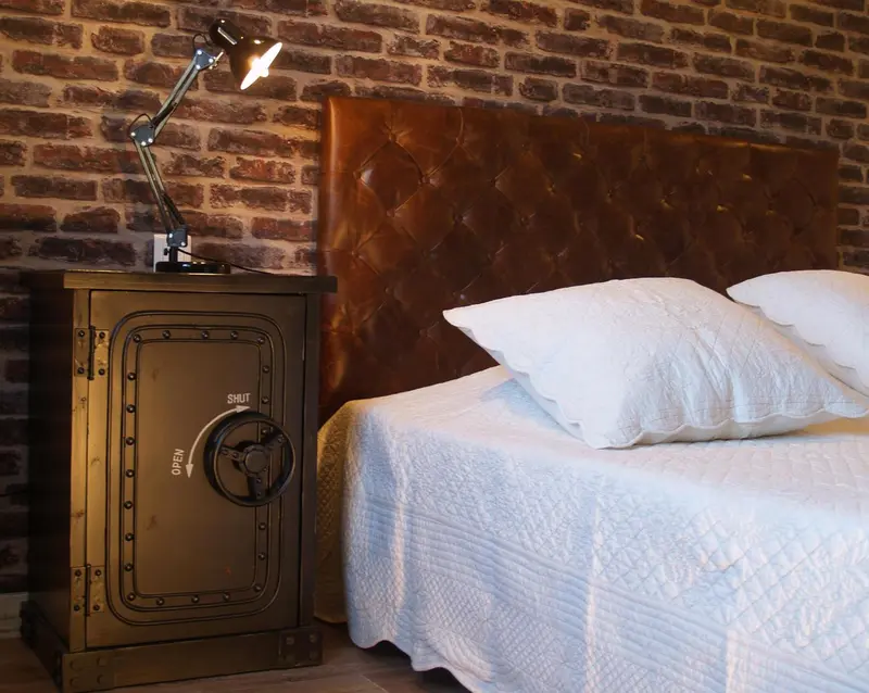 Une chambre avec un lit recouvert d'une couette blanche et une tête de lit en cuir marron.