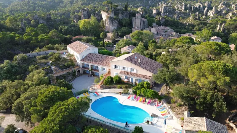 Vue aérienne d'une propriété avec piscine et végétation luxuriante.