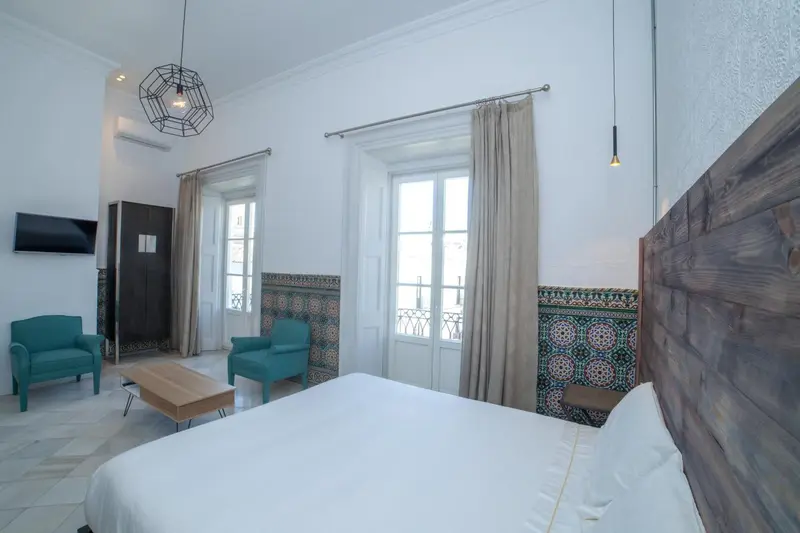 Une chambre lumineuse avec un grand lit et deux fauteuils.